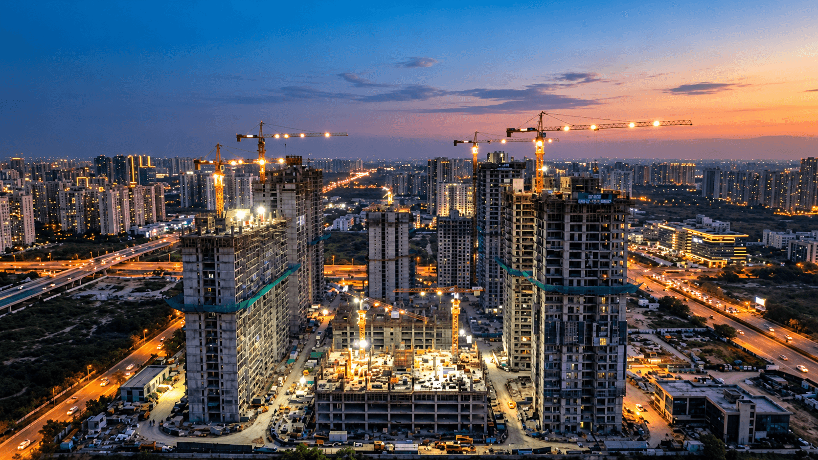 Tower under construction with cranes at dusk